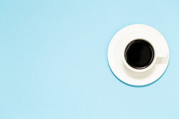 A cup of black coffee on blue background. View from above