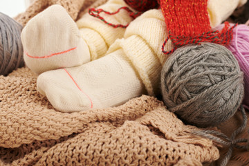 Child legs in warm socks are on a window sill with wool yarns.