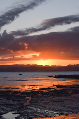 Fototapeta na wymiar A peach colored sunset reflected in the beach rock pools at Gisborne, New Zealand.