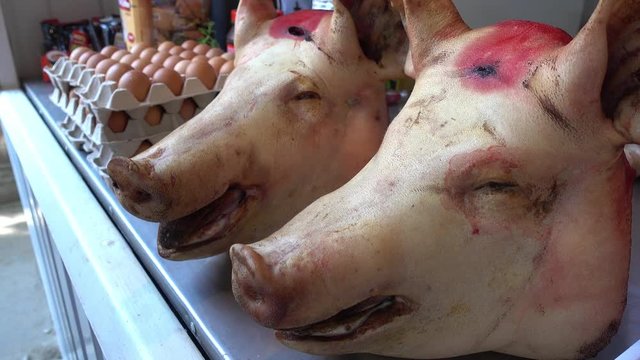 Kherson, Ukraine - 5th of June, 2017:  4K At the farmers product market - Close up two pig heads on counter for sale