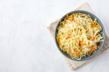 Bowl of fermented cabbage on plaster surface