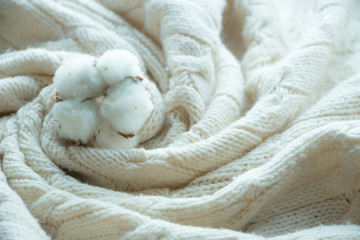 Cotton flower on beige knitted plaid with texture and pattern, hand made and cozy soft 