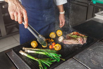 Chef cooking juicy beef steak at restaurant kitchen