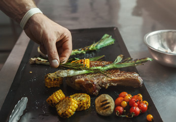 Chef cooking juicy beef steak at restaurant kitchen