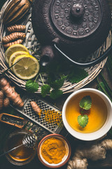 Cup of healthy turmeric spice tea with iron teapot and ingredients:  lemon,  ginger, cinnamon sticks and honey , top view.  Immune boosting remedy , detox and herbal medicine