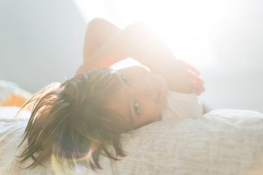 Cute little happy boy on bed with lens flare window