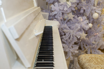 White Christmas tree decorated with silver and pink ornaments at the piano background.Winter scene. New Year decoration.Xmas interior design includes decorated Christmas tree.Selective focus.Classical