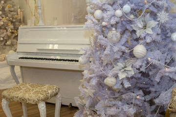 White Christmas tree decorated with silver and pink ornaments at the piano background.Winter scene. New Year decoration.Xmas interior design includes decorated Christmas tree.Selective focus.Classical