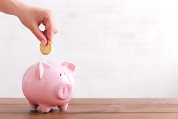 Hand put coin into pink color piggy bank