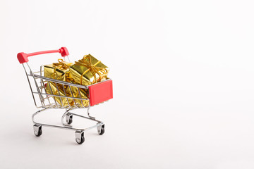 Shopping cart with golden Christmas gifts, isolated on white