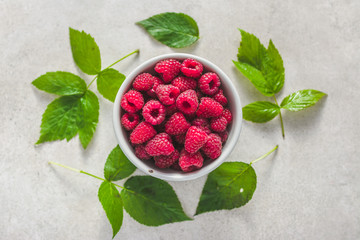 Fresh raspberries in a bowl and organic raspberry leaves