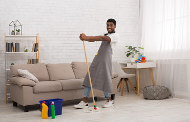 Black man with mop cleaning floor at home