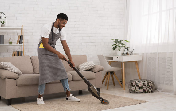 Black man cleaning house with wireless vacuum cleaner