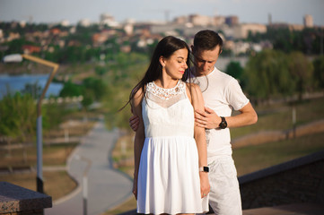 Love story of the beautiful young man and woman walking on the open air. embrace on a city walk.