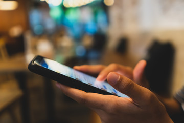 Woman hand using smartphone and laptop with cafe shop sunlight  shade to object beautiful background.