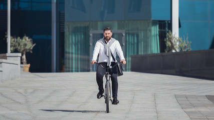 Active serious bearded businessman riding his bicycle