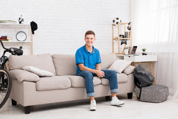Happy teen sitting on sofa in bedroom