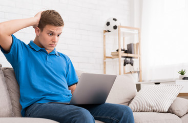 Surprised teenager having trouble with laptop at home