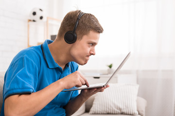 Concentrated teen boy playing video games on laptop
