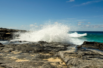 Adventure on the rocky coast near Playa de la Conchas beach on La Graciosa island, Canary Islands, Atlantic ocean, the strong waves are spreading over the rocks.