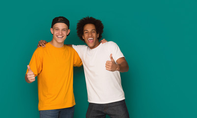 Teenage friends showing thumbs up over blue background - obrazy, fototapety, plakaty