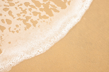 Fototapeta na wymiar Texture of wet yellow sand with sea wave foam