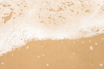 Texture of wet yellow sand with sea wave foam