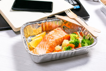 Healthy food delivery to workspace - containers, laptop, mobile phone, top view,
