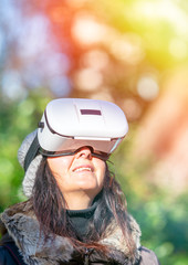 Happy woman wearing VR glasses exploring city park in winter