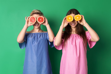Bright girls with halfs of fruits