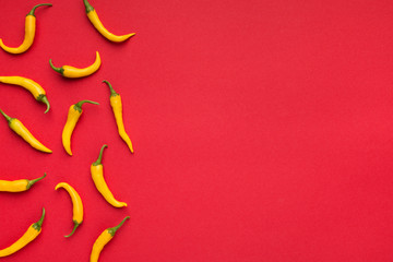 Hot yellow chilli peppers on red background
