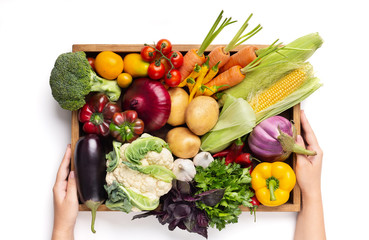 Farmer holding wooden box with crop of vegetables