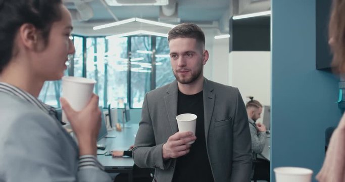 Three colleagues office workers having a conversation during a coffee break in a modern office. 4K UHD 60 FPS SLOW MOTION