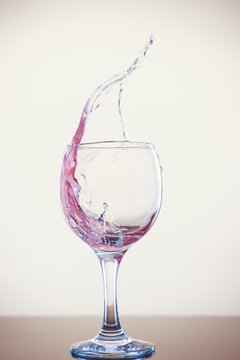 Splash of wine in a glass. Pink drink in glass on a white background.