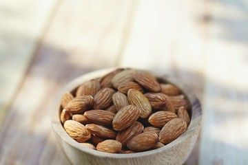 Almond nut in wooden bowl on wooden table background, copy space