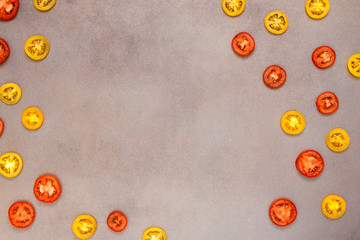 Red and yellow tomato slices on grey metallic surface. Top view, flat lay, copy space.