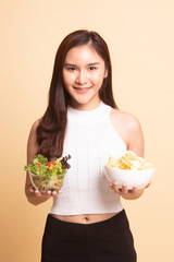 Young Asian woman with potato chips and salad.