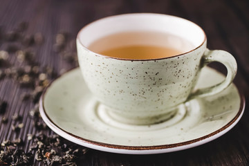 Cup of green tea and leaves of dry green tea on a brown wooden table. Superfood concept.
