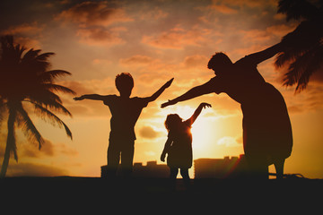 silhouette of family with kids play at sunset beach