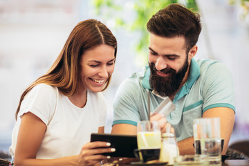 Beautiful couple having coffee on a date, using digital tablet and credit card for online shopping