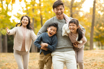 Happy young family playing in autumn woods