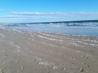 Schaumkronen am Strand vor einer aufgewühlten Nordsee