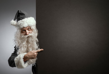 Black Santa Claus pointing at a blank sign