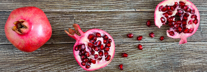 Ripe pomegranate fruit for making fresh pomegranate juice on wooden table. Healthy eating concept. The top view. Banner