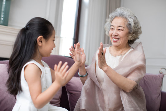 Happy grandmother and granddaughter playing clapping game - Powered by Adobe