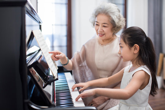 Grandmother teaching granddaughter to play the piano