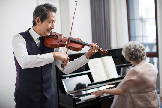 Noble senior couple playing the piano and violin