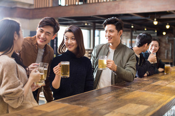 Happy friends drinking beer and talking in bar