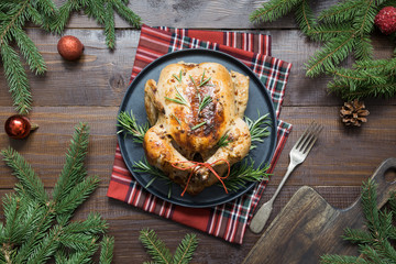 Traditional roasted chicken with spices and rosemary on wooden table. Top view.