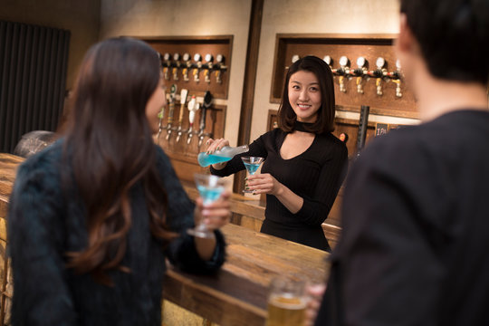 Smiling bartender mixing drink in bar